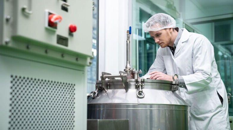 A lab worker helps create cannabis products at a machine